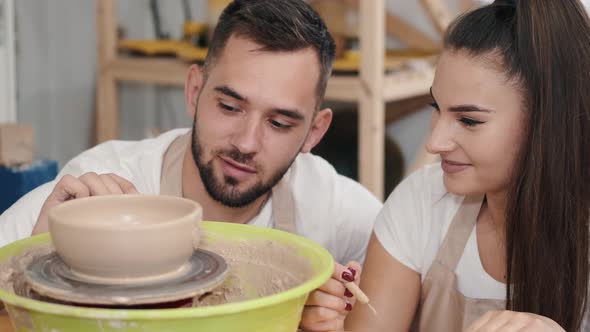 Loving Couple Carving on the Pottery Pot at a Workshop