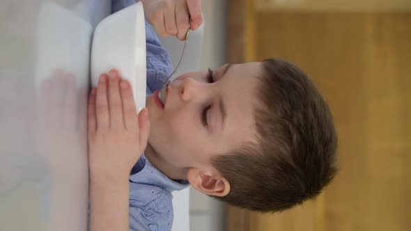 Small Hungry Boy Eating Tasting Sweet Corn Flakes with Milk at Morning