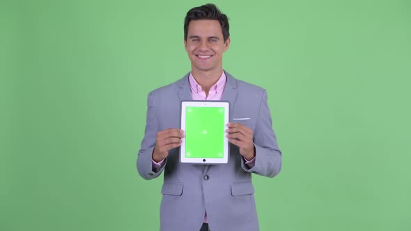Happy Young Handsome Businessman Talking While Showing Digital Tablet