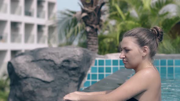 Young Woman in Black Bikini Relaxes Near Pool Barrier