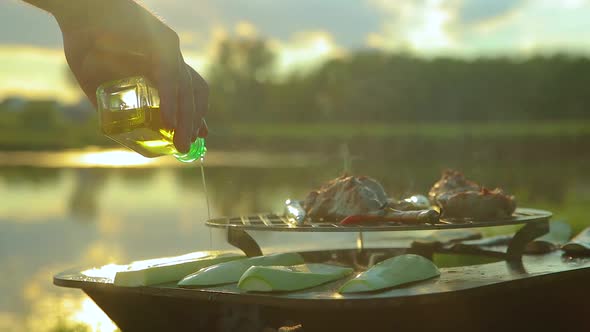 Man Pours Zucchini with Sunflower Oil on the Grill in Nature