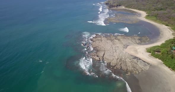 Aerial drone view of the beach, rocks and tide pools in Playa Palada, Guiones, Nosara, Costa Rica.