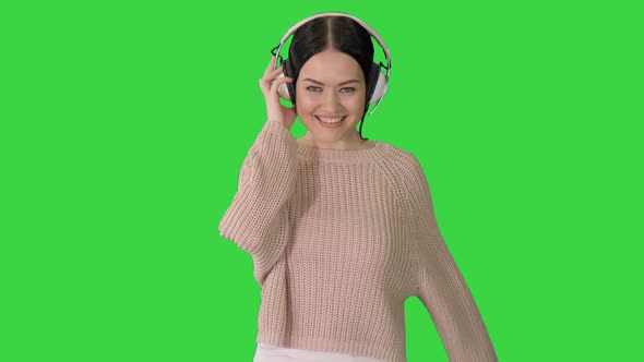 Smiling Female with Headphones Walking and Dancing To the Music on a Green Screen, Chroma Key.