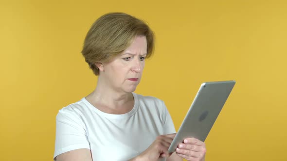 Old Woman Reacting to Loss on Tablet Isolated on Yellow Background