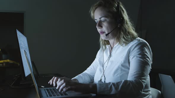 Focused Woman in Headset Using Laptop