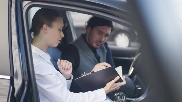 Side View Professional Female Secretary Passing Pen to Businessman Signing Documents Sitting in Car