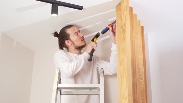 the Carpenter Nails with a Hammer Wooden Ash Lamellae to the Ceiling