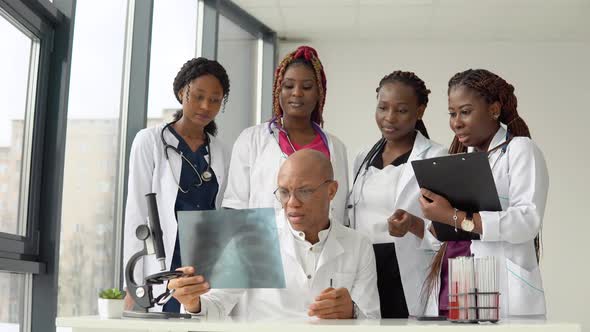 Five African American Doctors Man and Women Examine an Xray While Standing at a Table