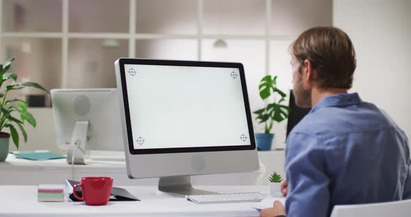 Caucasian businessman having video call meeting using desktop computer at desk in office