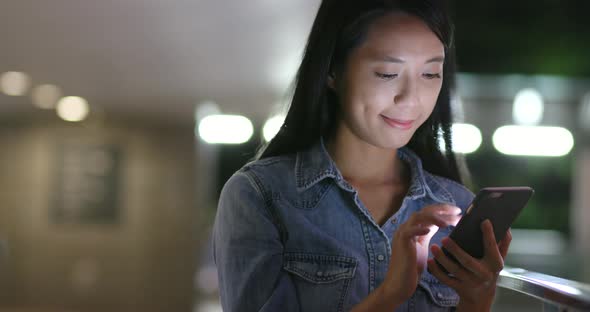 Woman use of mobile phone in city at night