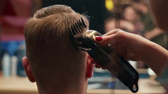 Barbershop: woman hairdresser cuts man's hair with a razor