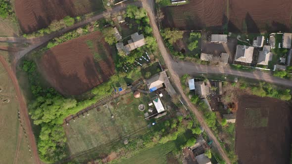 Aerial View of Houses Amidst Green Trees and Fields in the Countryside