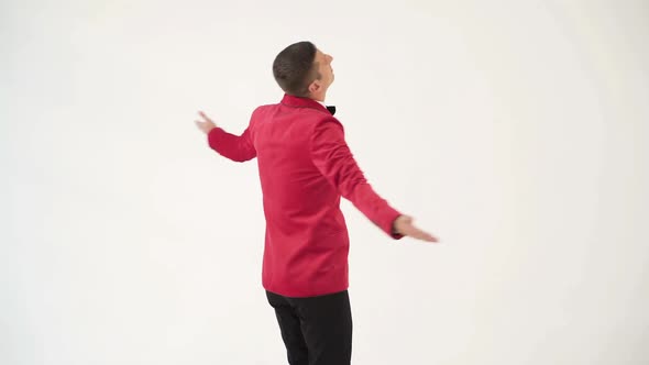 showman in a red jacket with a bow tie is circling around himself with openarmed hands