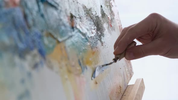 A Young Male Artist Works in a Studio He Uses Bright Paint on a Large White Canvas