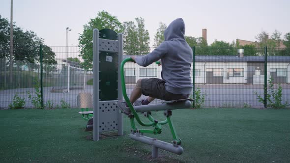 Man using a rowing machine. Evening workout in an outdoor gym. Health and fitness