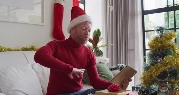 Happy albino african american man wearing santa hat making video call at christmas