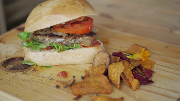 Slow pan of farm-stall beef burger and dry vegetable chips