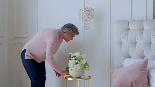 Elderly Woman Wipes a Table with a Rag at Home. Concept of Home Work and Household Management