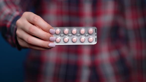 Woman Presenting a Hand of Foil-wrapped Pills