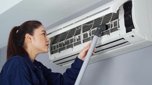 female technician service using vacuum cleaner to cleaning the air conditioner