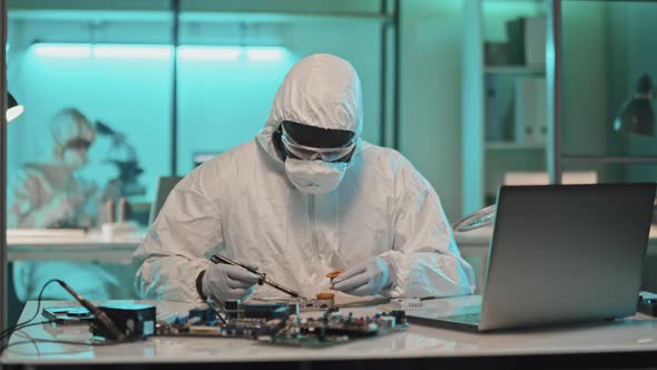 Engineer in Protective Suit Soldering Electronics in Lab