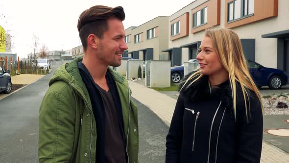 A Man and a Woman Talk on a Road in a Neighborhood