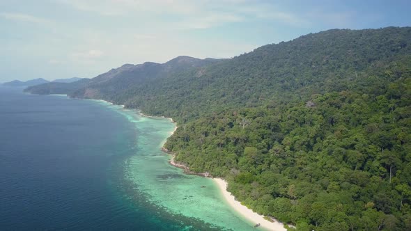 Aerial view of long lush island with vegetation and beautiful waters in Thailand - lateral tracking