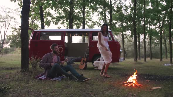 Happy Young Cheerful Mixed Race Couple Having Some Fun in Retro Hippie Minibus in Forest