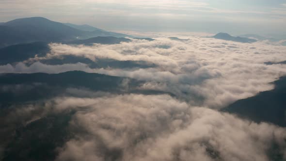 Low clouds and morning mists over mountain slopes at sunrise