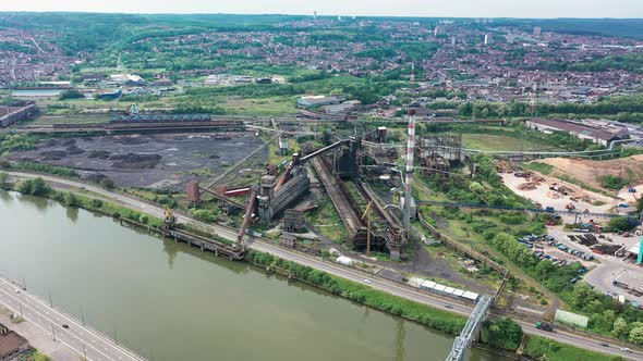 Aerial view of abandoned steel factory with urban background. Next to river and highway with cars dr