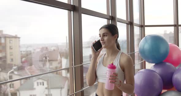 Sporty Girl Drinking Water and Talking By Phone