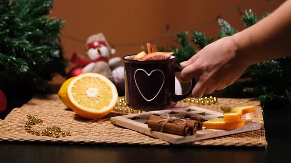 Female Putting Mugs with Mulled Wine on Table