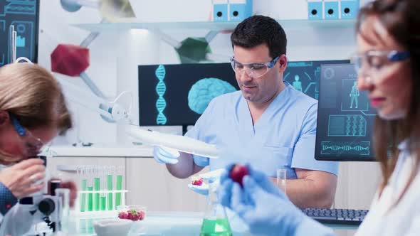 In Busy Food Genetics Laboratory Assistant Is Looking at a Fruit Sample Under the Magnifying Glass alt