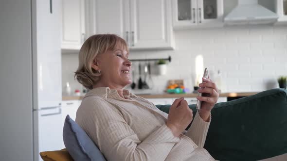 Excited Female Sitting On Couch With Phone Beside Herself With Joy Of Success