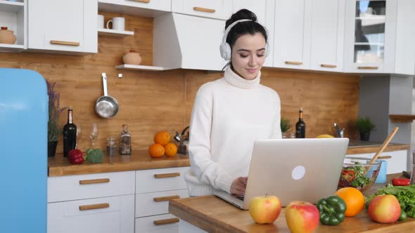 Young Woman Using Laptop While Cooking In Kitchen.