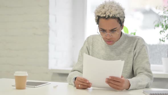African Woman Upset While Reading Documents in Office