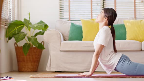 Asian woman in casual doing yoga Cobra pose at home