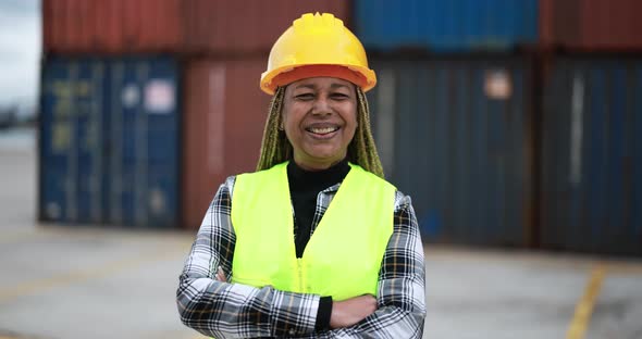 Worker African senior woman smiling on camera with industrial port on background