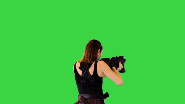 Cyberpunk Girl in Black Military Clothes Walks with Machine Gun Taking an Aim on a Green Screen alt