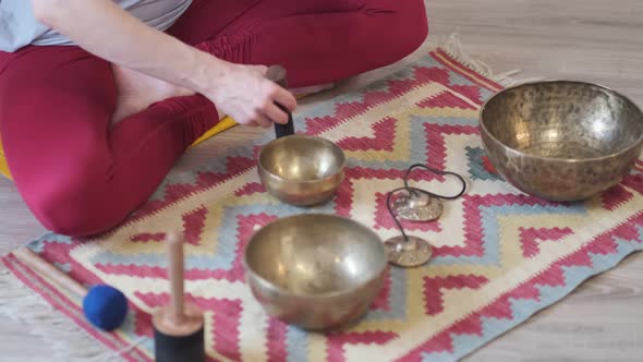 Woman Playing on Tibetan Singing Bowl While Sitting on Yoga Mat