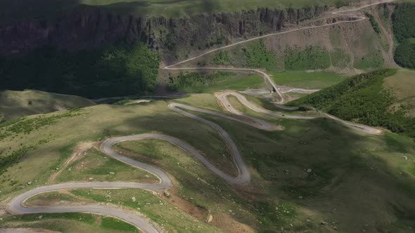 Top view of the mountain road through the green field