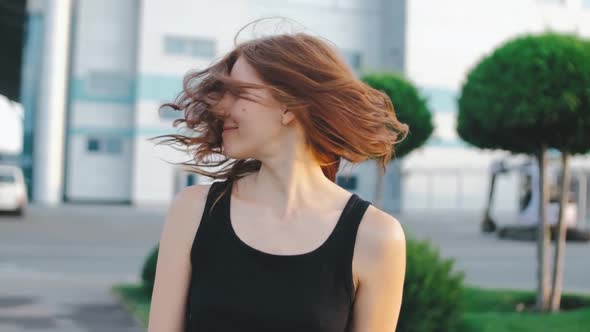 Beautiful Redhaired Woman with Long Hair on Street at Sunset