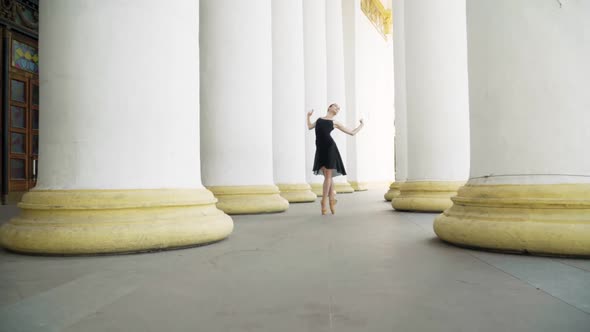 Camera Approaches To Slim Confident Ballerina Dancing Between White Columns