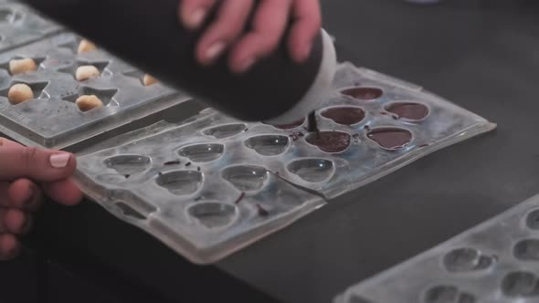 Close up shot of woman pouring fresh chocolate into heart molds.Cooking desserts from chocolate and