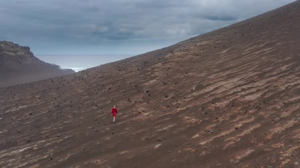 Tourist in Red Sweatshirt Walks Across the Volcanic Hill