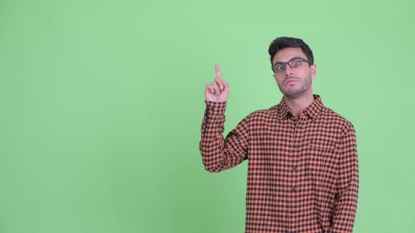 Stressed Young Hispanic Hipster Man Pointing Up and Giving Thumbs Down