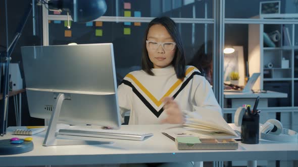 Beautiful Asian Woman Working with Computer Typing Then Writing in Notebook Focused on Job in Office