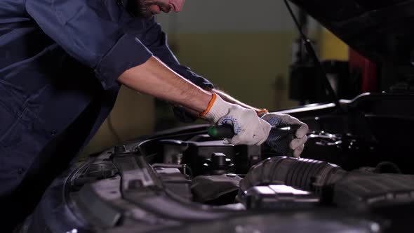 Auto Mechanic Working with Wrench Under Car Hood