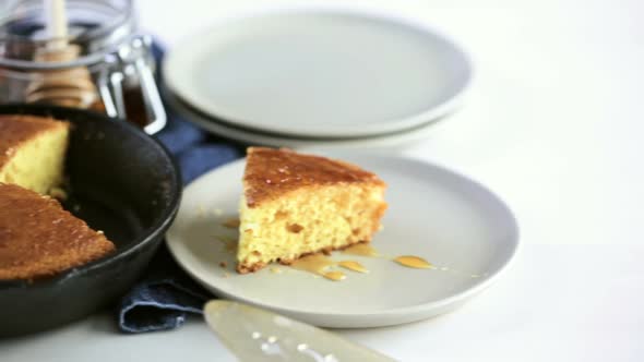 Slice of sweet cornbread with honey on the plate