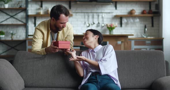 Loving Husband Man Making Surprise Giving a Present to His Wife at Home